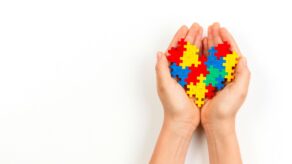 A pair of hands holding coloured jigsaw pieces.